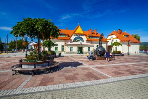 Odrestaurowany budynek dworca PKP, przed nim pomnik św. Mikołaja.