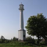 Zdjęcie przedstawiające obelisk Szwedzką Kolumnę w Kamionnej zbudowaną w stylu toskańskim w 1656 roku. Dziesięciometrowa kolumna wspiera się na czworobocznym cokole, zwieńczona jest abakusem i czworoboczną ażurową latarnią, nakrytą piramidalnym daszkiem i krzyżem. Zdjęcie wykonane w letniej szacie. Słońce pada na obelisk z lewej strony obejmując mniej więcej połowę obelisku dzięki czemu gra cieni uwydatnia piękno zabytku.
