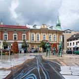 Zdjęcie przedstawia plytę Rynku Górnego w Wieliczce pokrytą trójwymiarowym malowidłem przedstawiającym wnętrze kopalni. W tle kamieniczki przy Rynku.