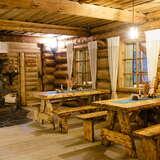 Wnętrze restauracji - ściany z bali drewnianych, drewniane stoły i ławy, kamienny kominek.