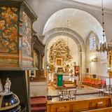 Wnętrze kościoła. Bogato zdobiony ołtarz główny z obrazem Matki Boskiej, proste ołtarze boczne, ściany pokryte tynkiem. Po lewej widoczny fragment ambony.