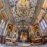 Wnętrze drewnianego kościoła, bogato, barwnie polichromowane. Widać barokowe złocone ołtarze.