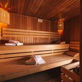Widok na sauna w termach Gorce. Drewniany podest z ławkami na których położona są ręczniki z logo term.