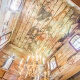 Wnętrze drewnianego kościoła - drewniany sufit i ściany pokryte polichromią ornamentalno-figuralną w stonowanych kolorach.