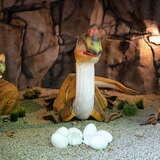 Trzy figurki małych dinozaurów obok skorupek jaj